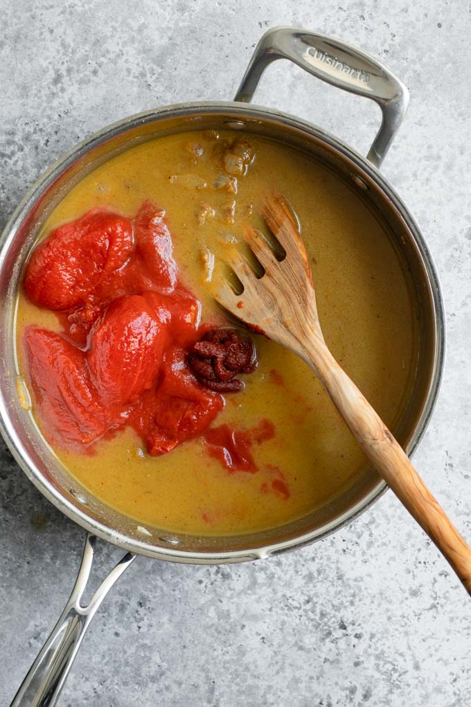 adding tomatoes and tomato paste to sauce