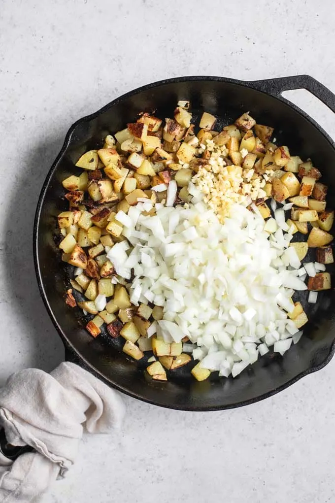 fried potatoes in skillet with onions and garlic added