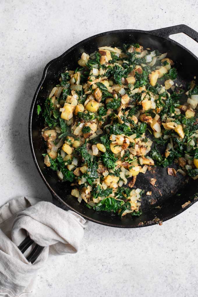 cooked potatoes, onion, garlic, and kale in skillet
