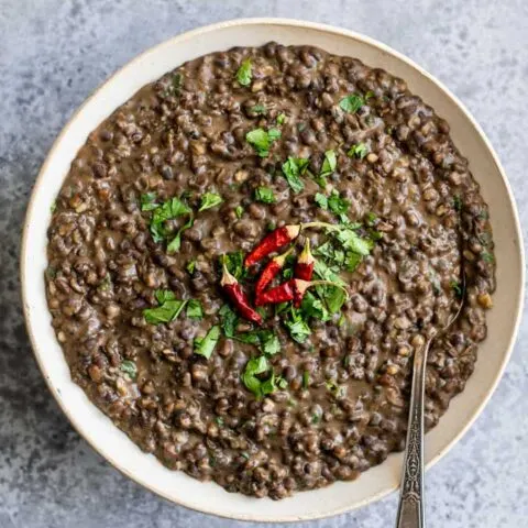 garlic urad dal fry in a serving bowl garnished with cilantro and dried red chiles
