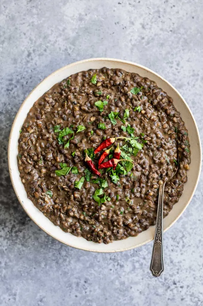 garlic urad dal fry in a serving bowl garnished with cilantro and dried red chiles