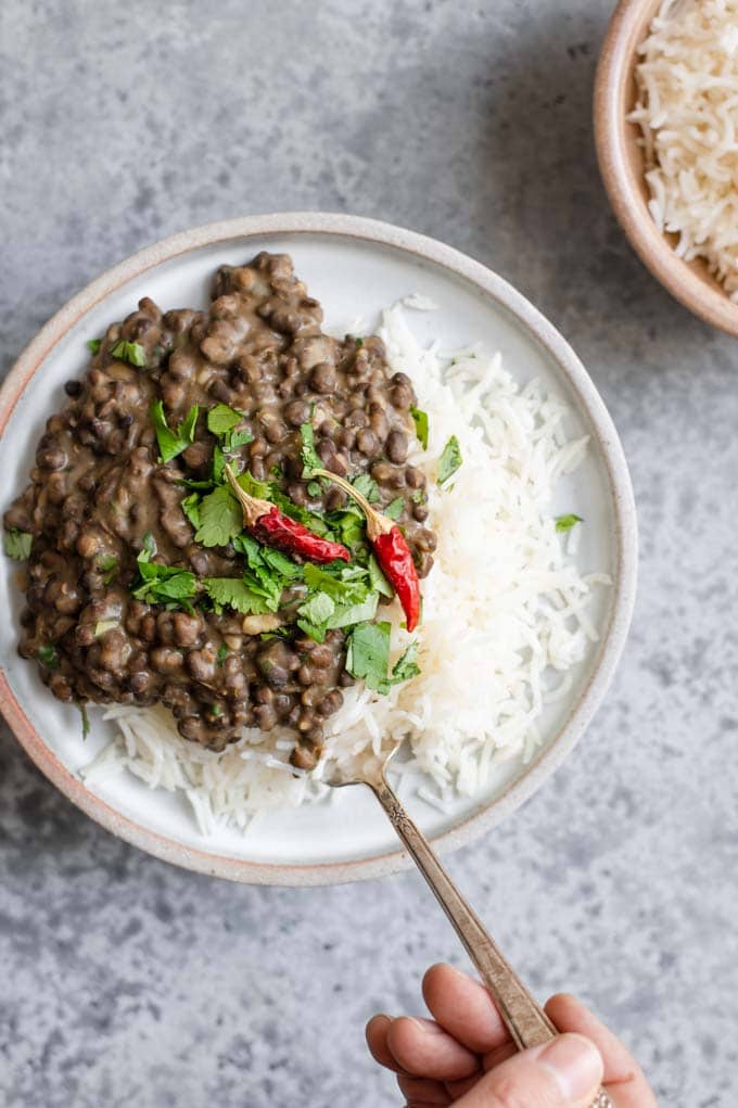 scooping up a forkful of urad dal and rice