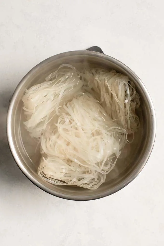 dry rice noodles submerged in boiling water