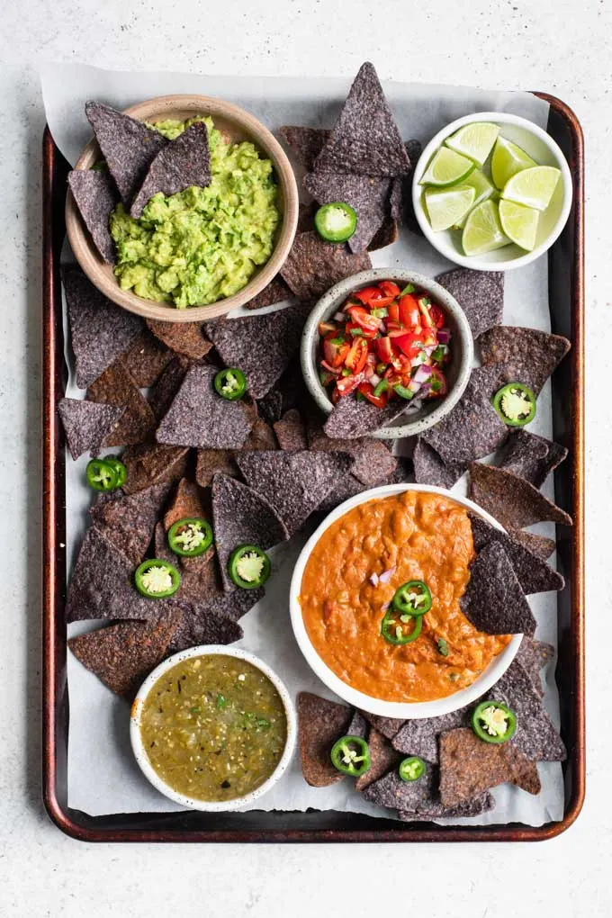 chip and dip spread with blue corn chips, bean dip, pico de gallo, salsa verde, and guacamole