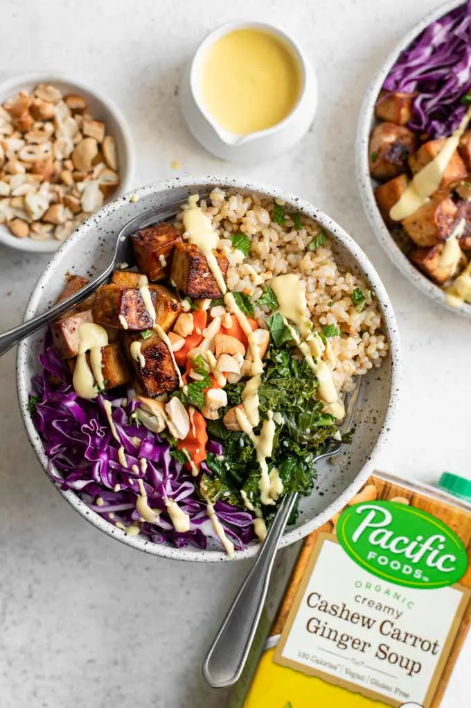 tofu buddha bowls drizzled with carrot ginger dressing and the box of Pacific Foods Cashew Carrot Ginger Soup used to make dressing