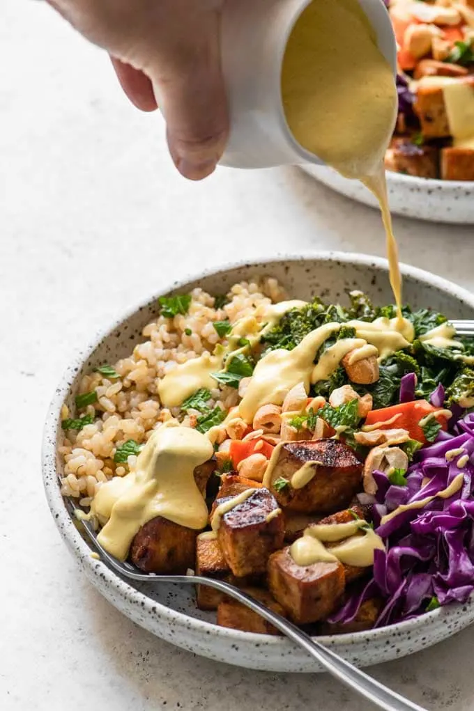 pouring dressing over tofu bowls