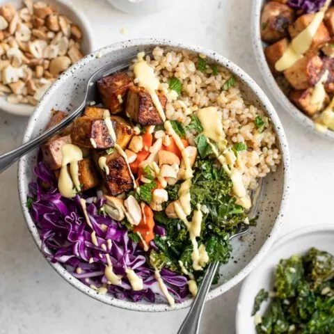 tofu buddha bowls with carrot ginger dressing and bowls of sesame kale and roasted cashews