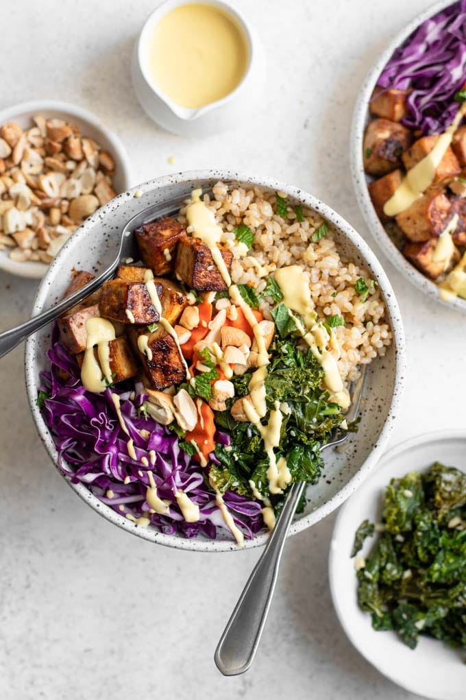 tofu buddha bowls with carrot ginger dressing and bowls of sesame kale and roasted cashews