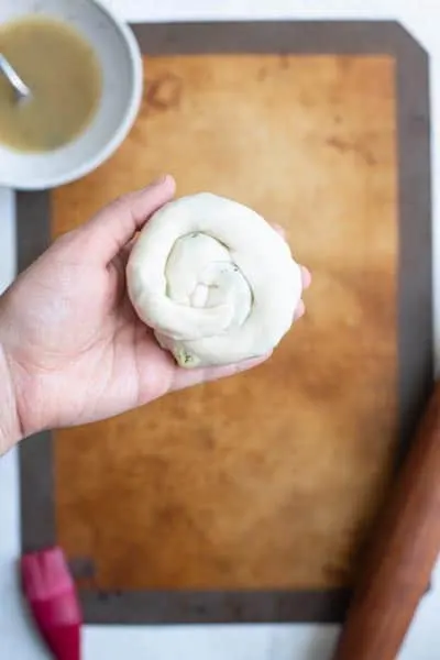 scallion pancake spiral picked up to show the bottom side with the end tucked under