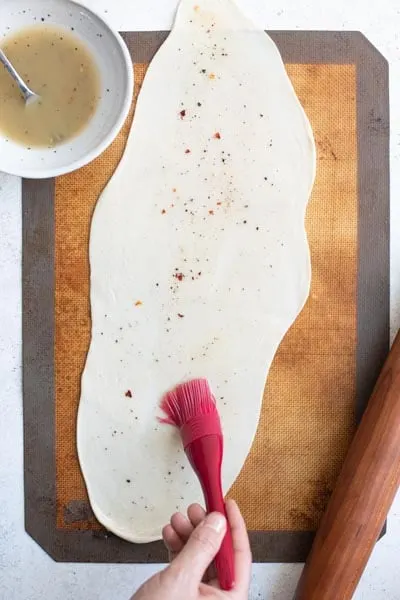 pancake dough rolled into rectangle and being brushed with the seasoned flour-oil mixture