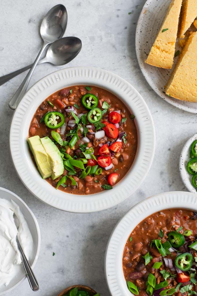 meaty vegan chili topped with avocado, cherry tomatoes, jalapeño, scallion greens, and cilantro and served with cornbread