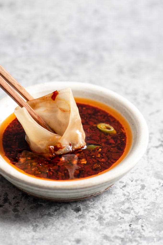 dipping a wonton into the spicy sauce