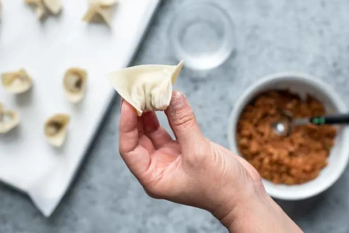 dumpling wonton shape folding step 3: wet bottom corners and pinch to meet