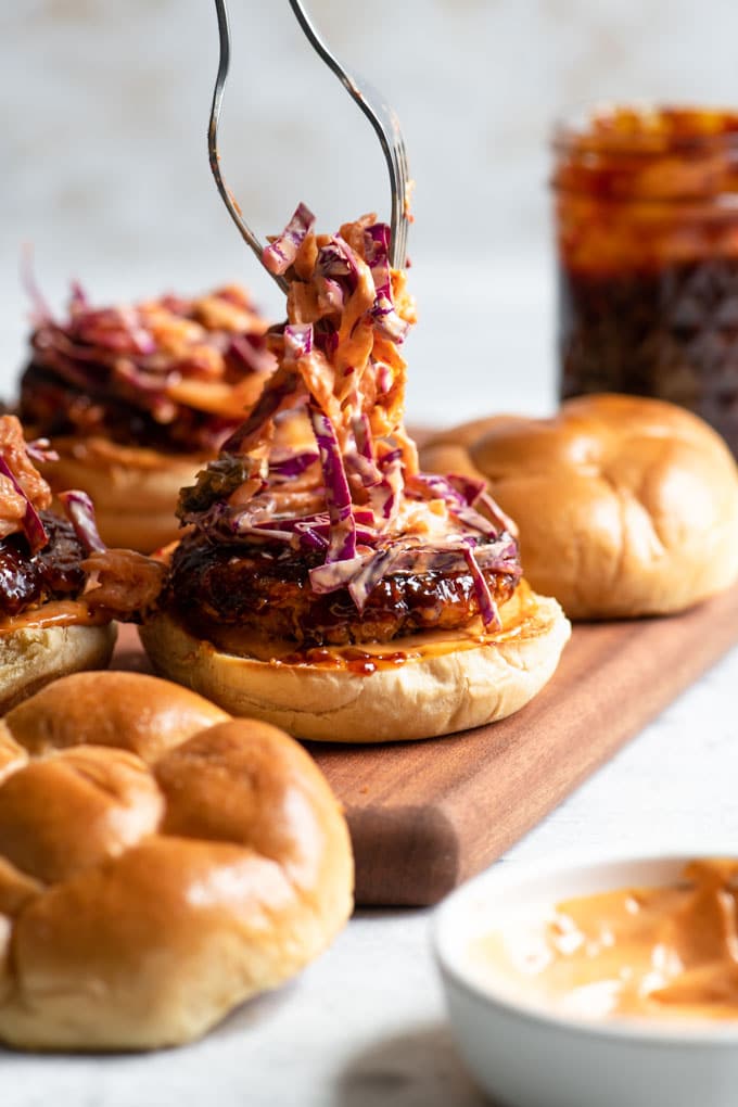 putting kimchi slaw on top of tempeh burgers