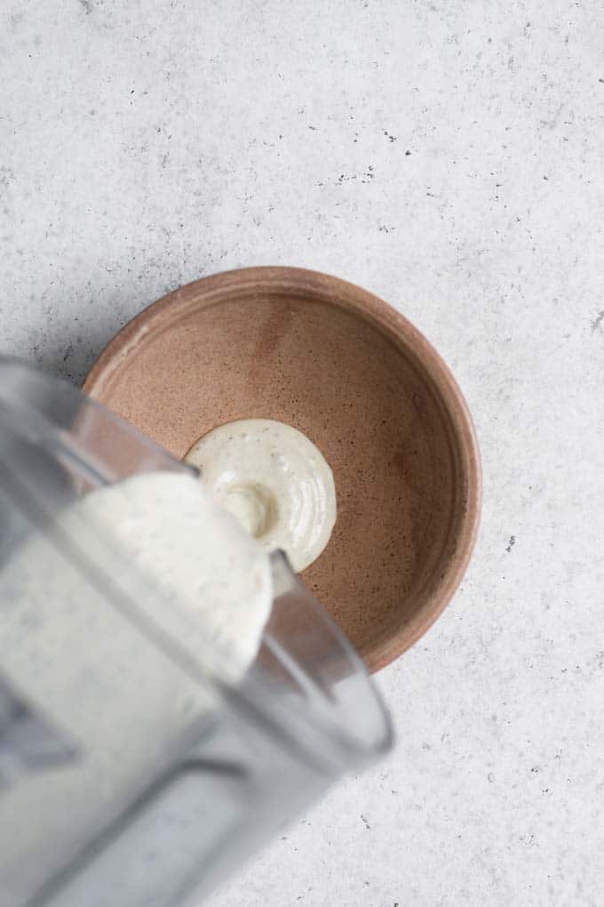 pouring dressing from blender into small bowl