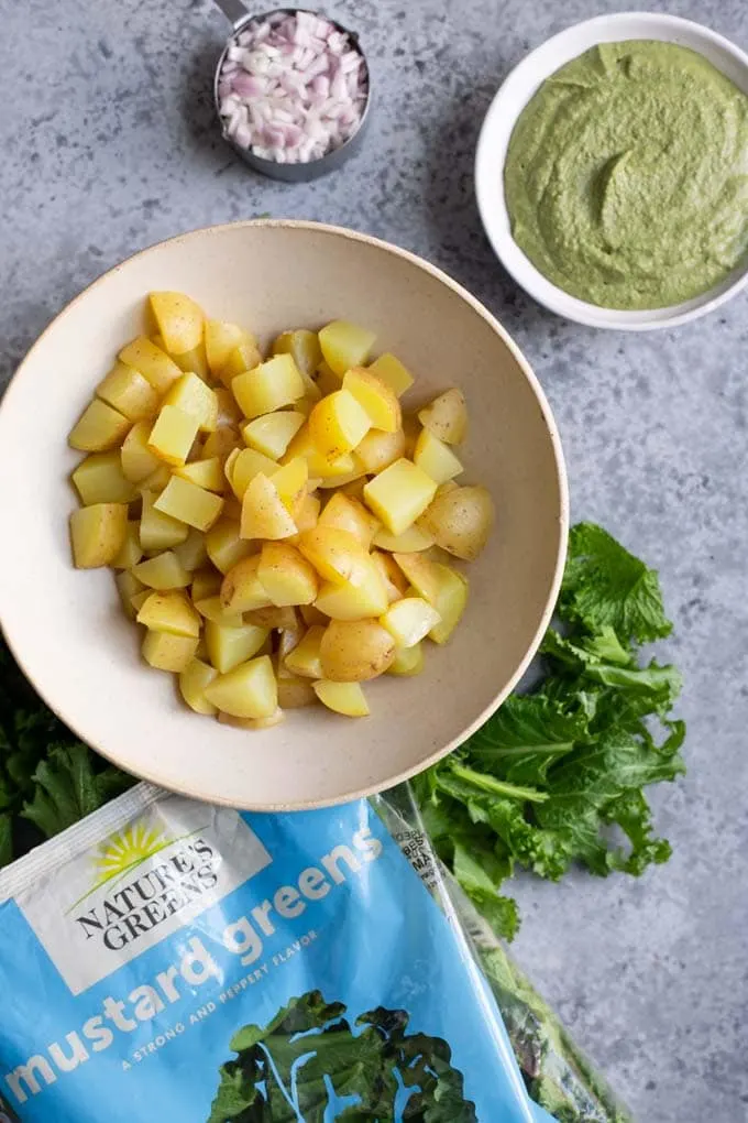 ingredients for pesto potato salad: steamed potatoes, mustard green pesto, and minced shallot