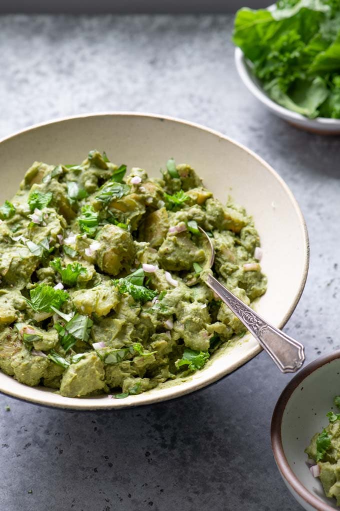 mustard green pesto potato salad with bowl of mustard greens in background