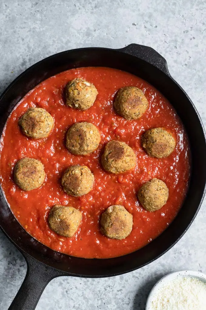 chickpea meatballs placed in pan with tomato sauce, before cooking