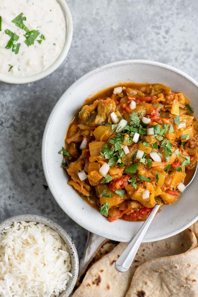 Indian eggplant dish served with chapati, rice, and raita