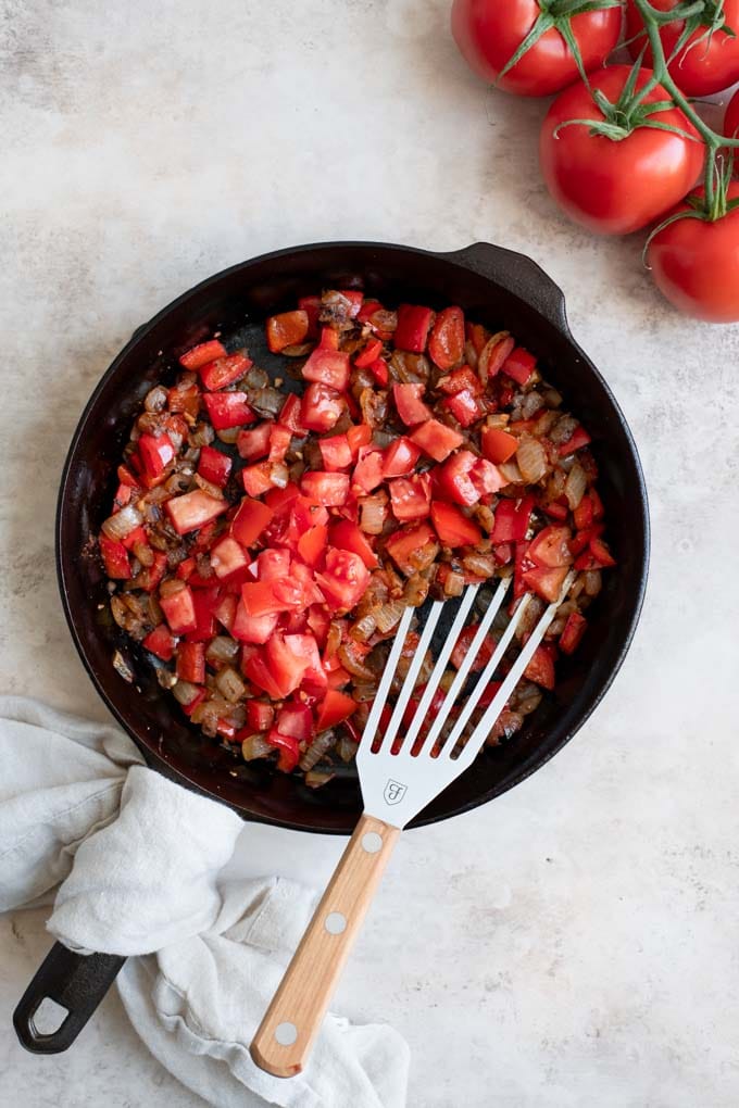 fried onions and bell pepper with tomatoes added in skillet