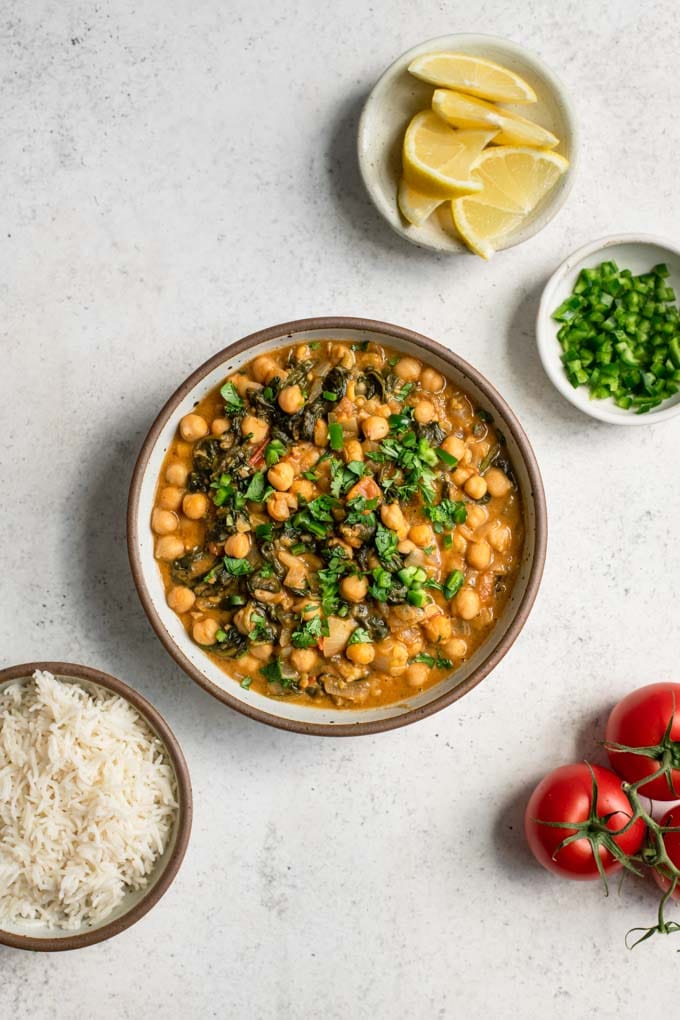 chickpea curry served with rice, lemon wedges, and minced pepper