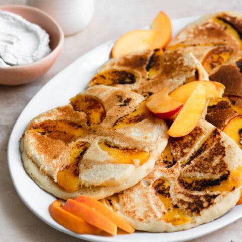 peach pancakes served with whipped coconut cream and maple syrup