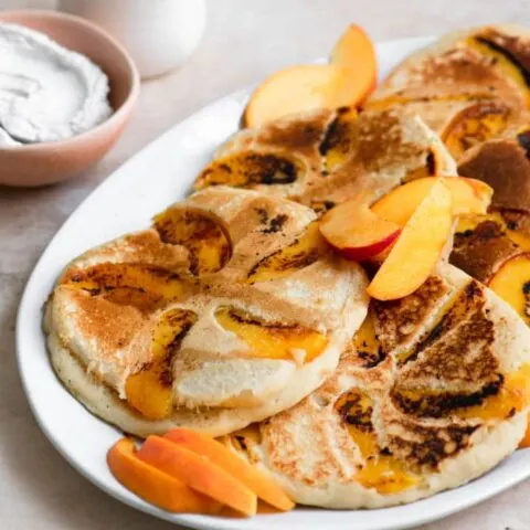 peach pancakes served with whipped coconut cream and maple syrup