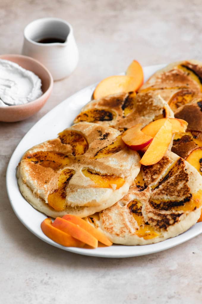 peach pancakes served with whipped coconut cream and maple syrup