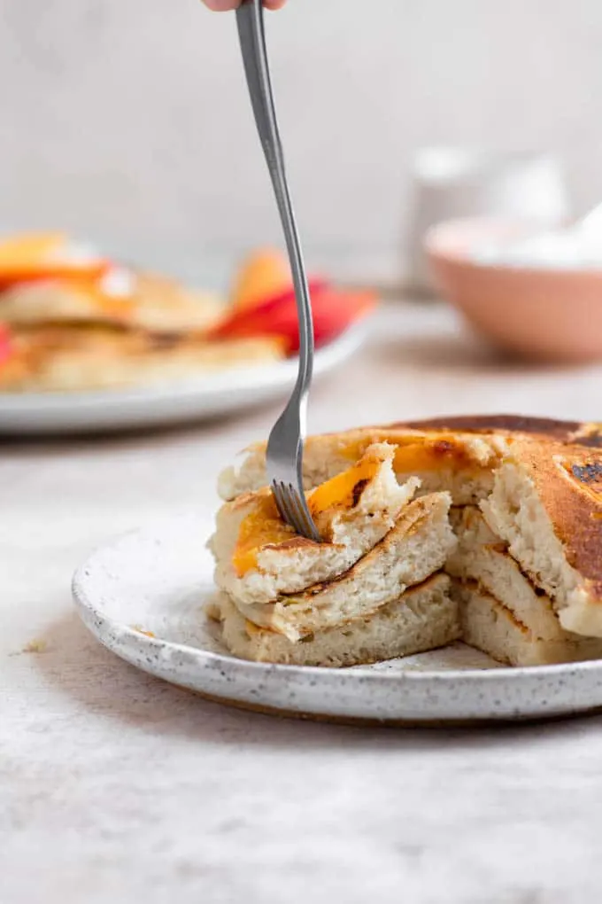 digging a fork into a cut piece of a stack of 3 pancakes