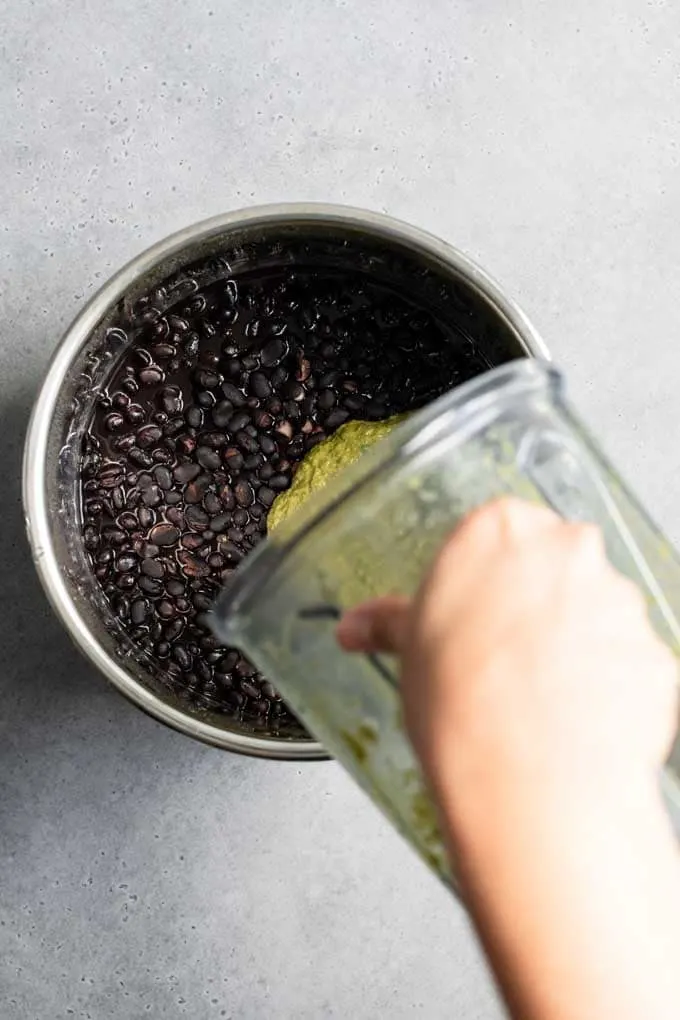 pouring seasoning into black beans
