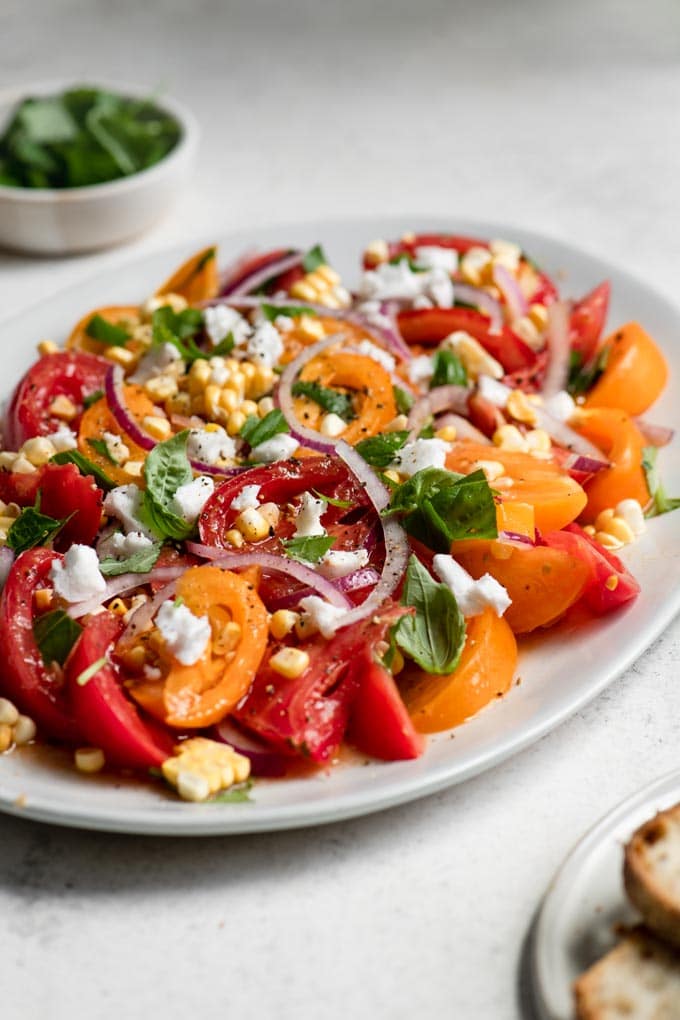 side view of sweet corn and tomato salad garnished with vegan feta