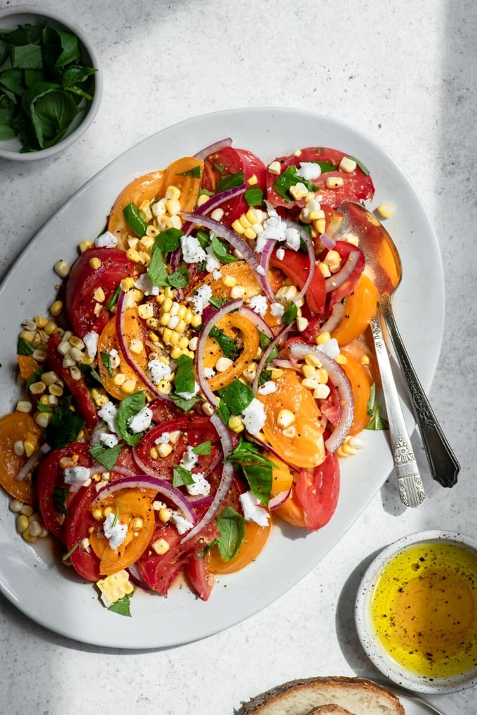 tomato corn salad on oval serving dish in direct harsh lighting