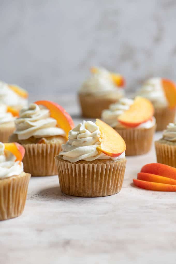 peach cupcakes frosted with a peach slice resting on frosting