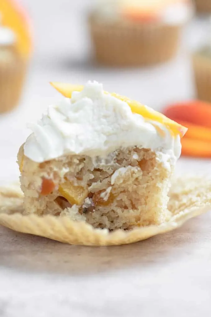 bite shot showing crumb and pieces of peach inside the cupcake