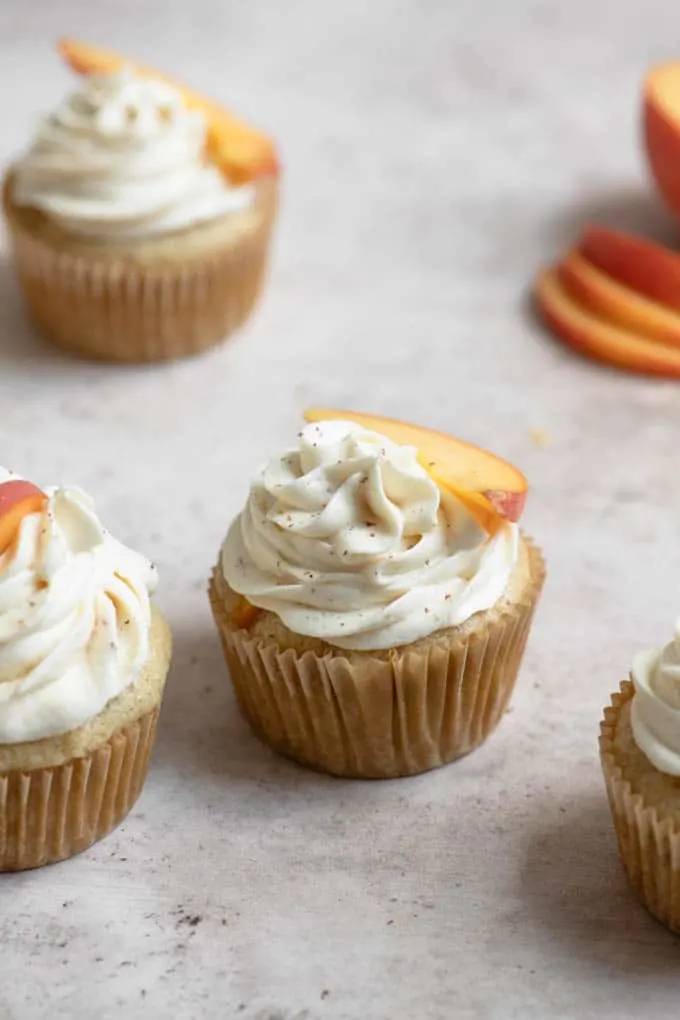 3 peach cupcakes and some sliced peaches