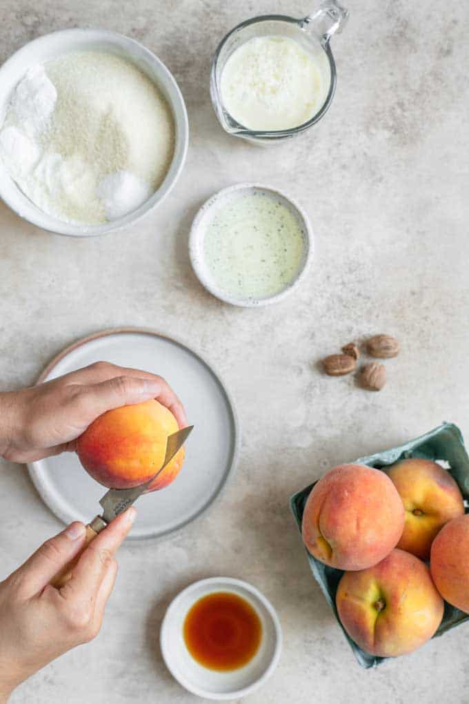 cutting a peach over a plate with the cake ingredients in photo