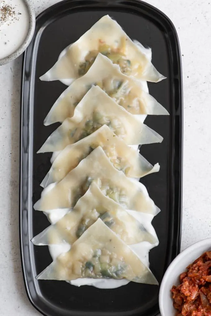 dumplings on platter over vegan yogurt sauce