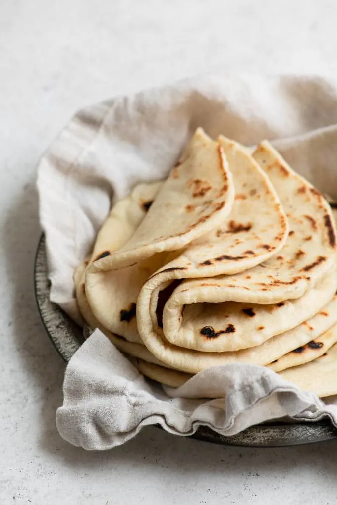 three flatbreads folded in half on top of a stack of flatbreads