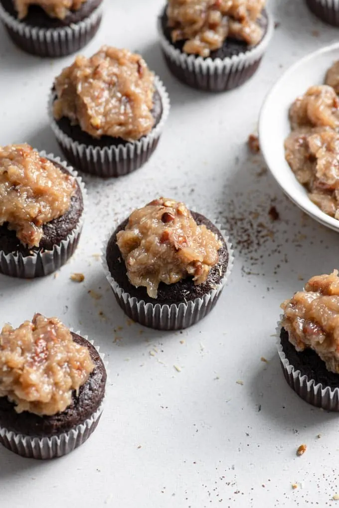 vegan german chocolate cupcakes with small bowl of frosting