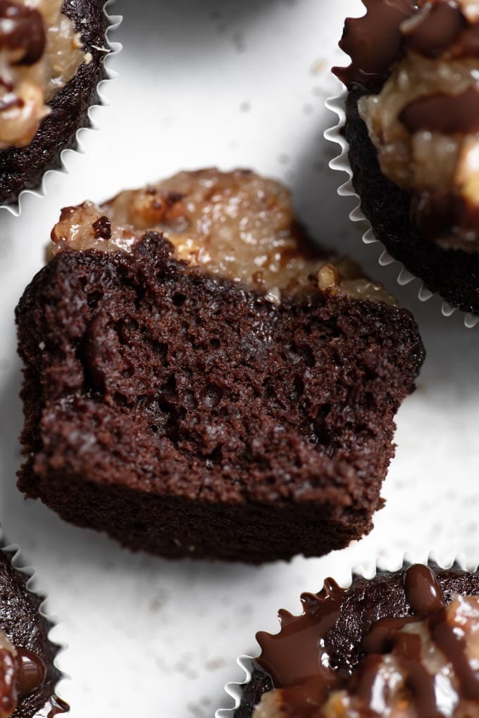 close up of german chocolate cupcake on its side with a bite taken out of it showing the crumb