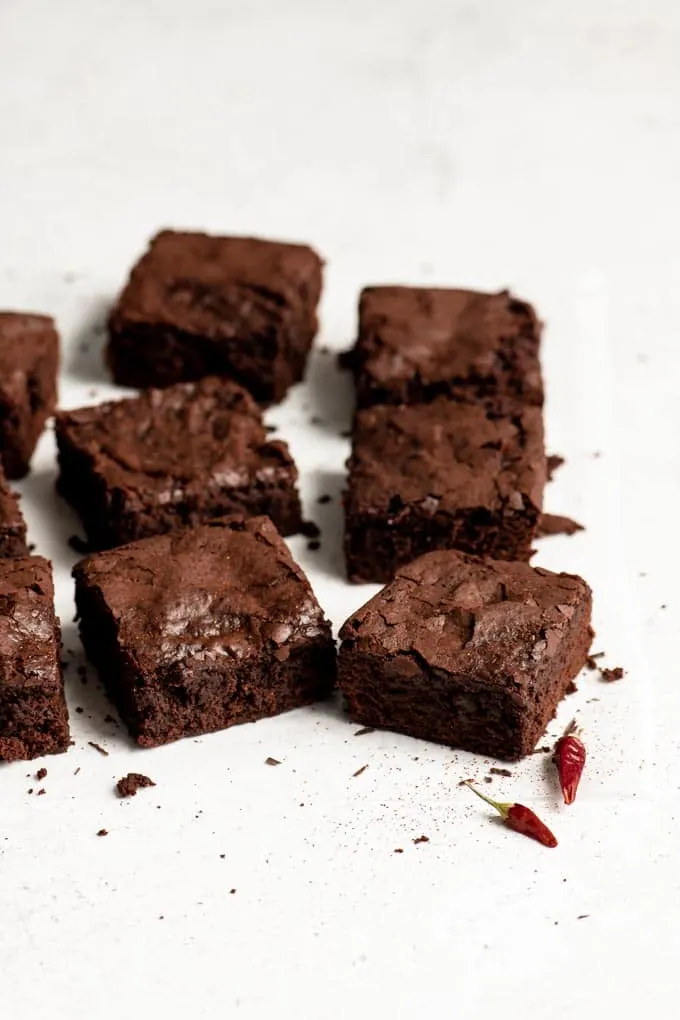 vegan brownies cut and on parchment paper with dried chiles sitting next to them