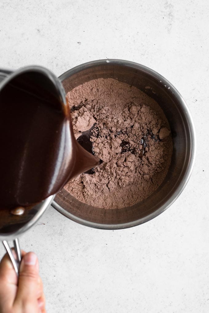 pouring melted chocolate, sugar, and liquid mixture into dry brownie ingredients