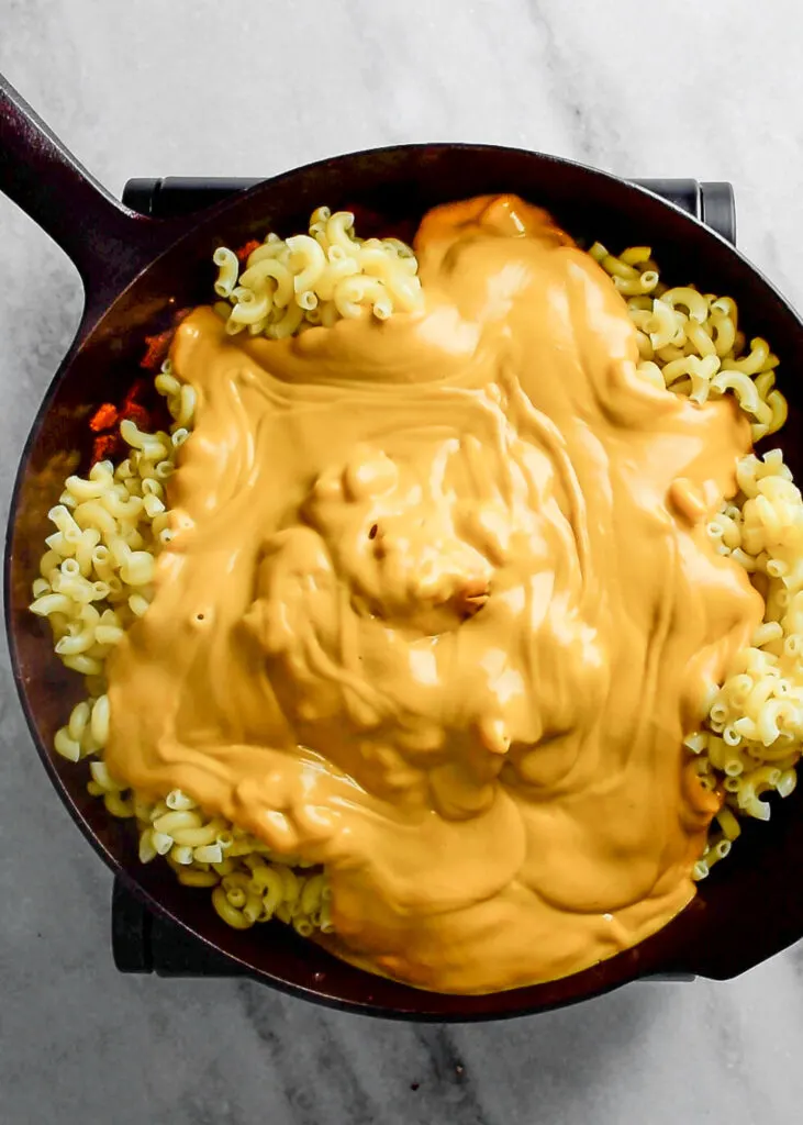 cheese sauce poured on macaroni in skillet