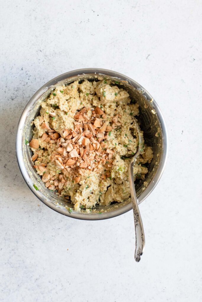 tofu salad in mixing bowl with final ingredient of chopped cashews added on top