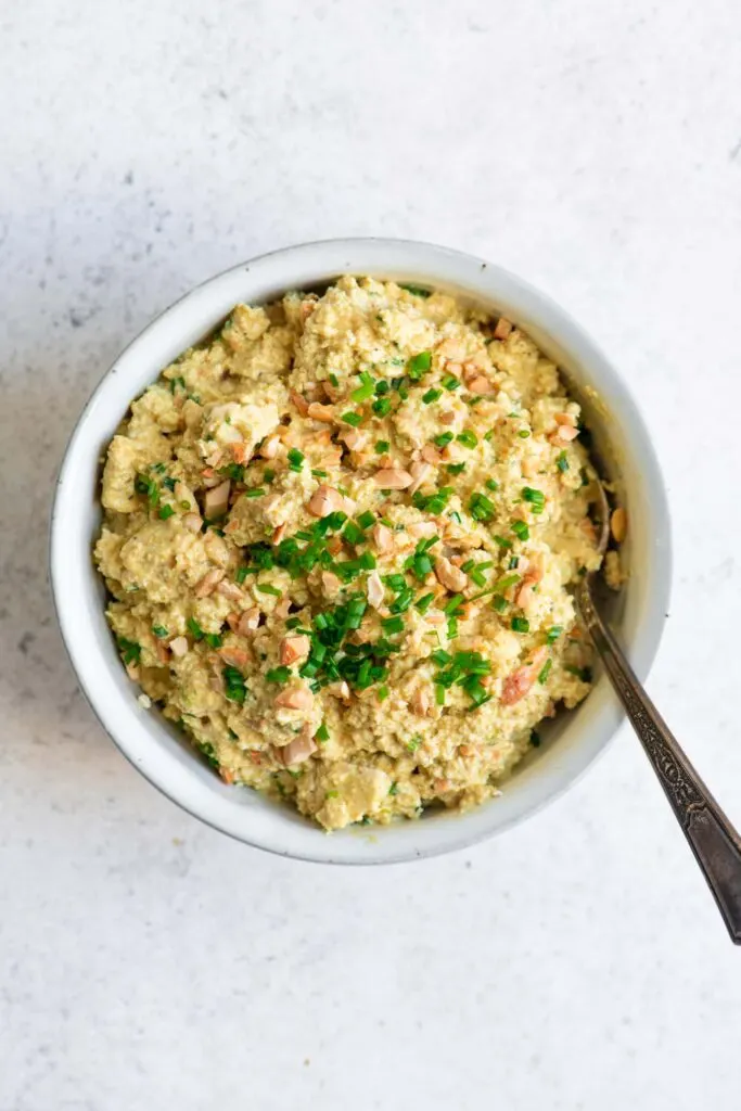 curried tofu salad in bowl garnished with chives and roasted cashews