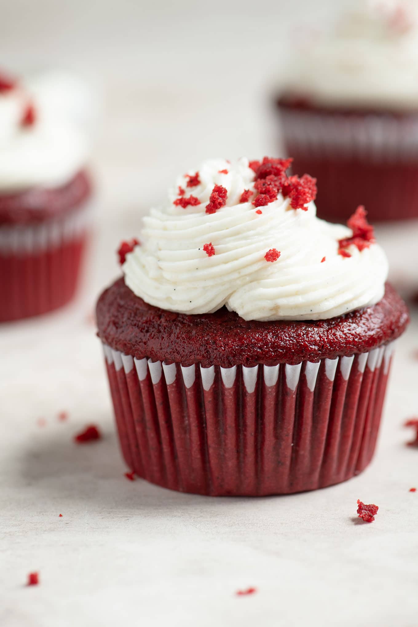vegan red velvet cupcake sprinkled with red cake crumbs on top of the frosting