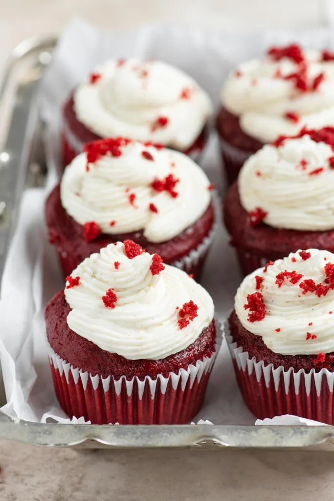 six frosted vegan red velvet cupcakes in a metal serving dish