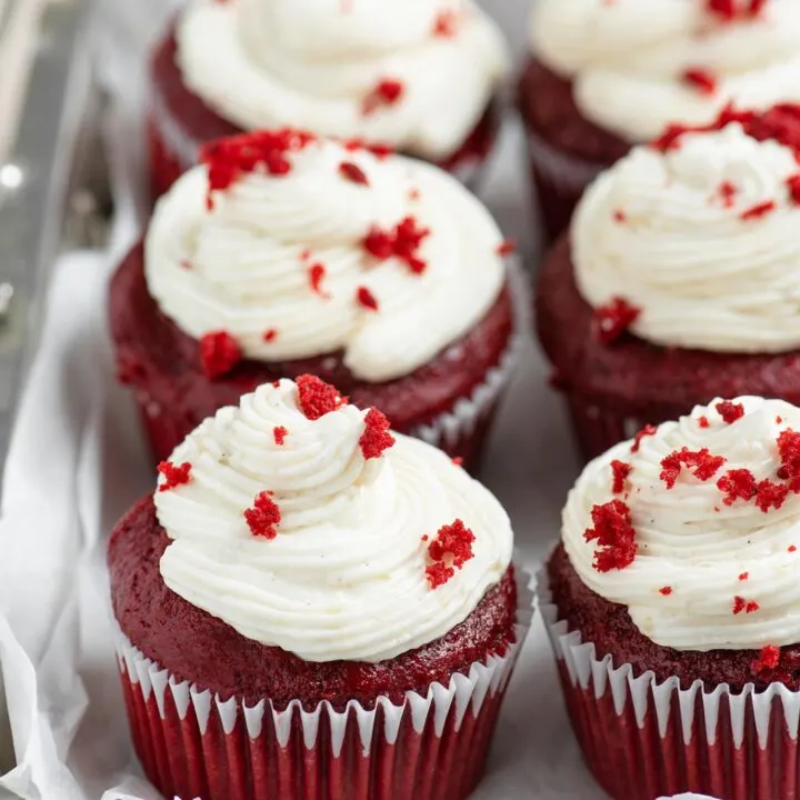 six frosted vegan red velvet cupcakes in a metal serving dish