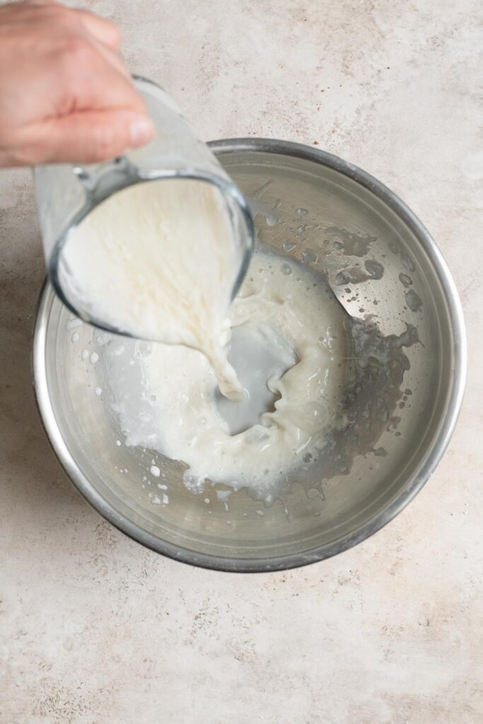 pouring curdled soy milk into large mixing bowl