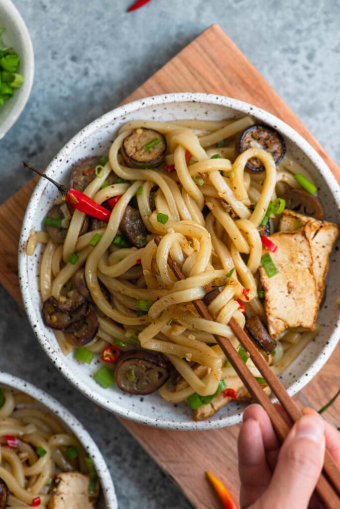 overhead shot of noodles being pulled up by chopsticks